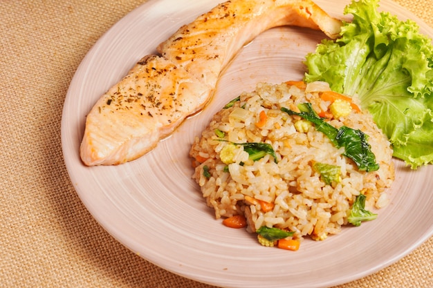 Leckeres Abendessen oder Mittagessen, gesundes asiatisches Essen. Gegrillter Lachs mit japanischem gebratenem Reis und Gemüse