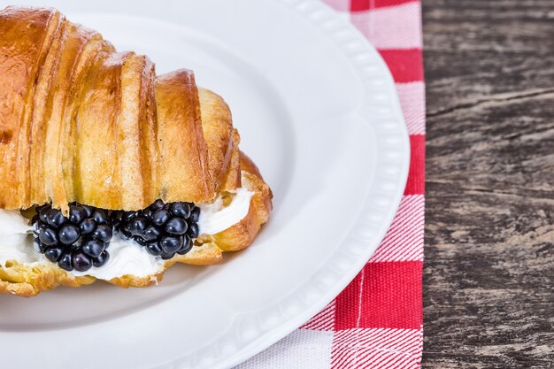 Leckeres Croissant mit Sahne und Blaubeeren. Zum Frühstück.