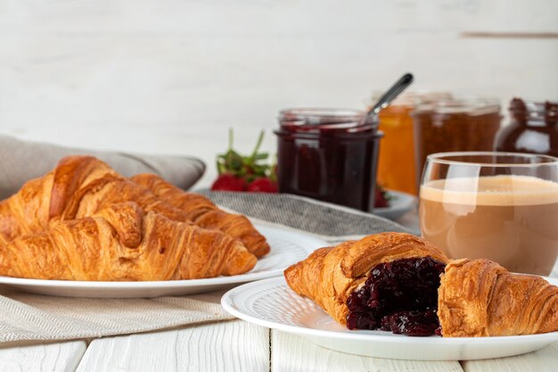 Leckeres Croissant mit Tasse Kaffee mit Milch auf Küchentisch