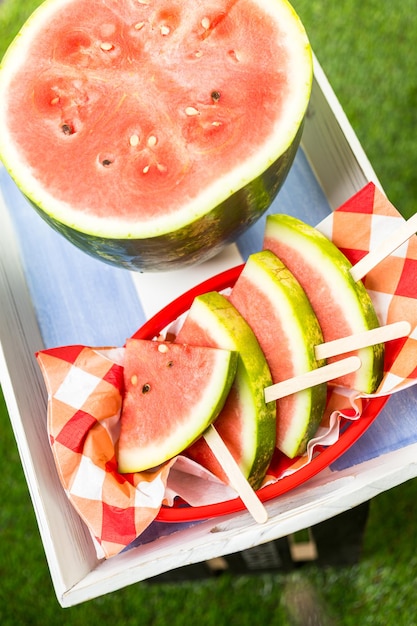 Leckeres Eis am Stiel in Wassermelonenscheiben für den erfrischenden Genuss beim Sommerpicknick.