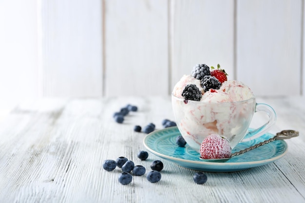 Leckeres Eis mit frischen gefrorenen Beeren auf farbigem Holzhintergrund