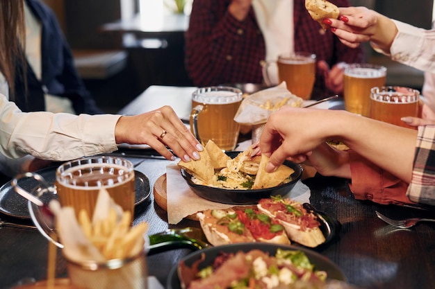 Leckeres Essen Gruppe junger Freunde, die zusammen in der Bar mit Bier sitzen