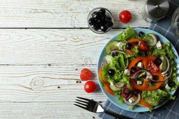 leckeres Essen mit griechischem Salat auf weißem Holztisch