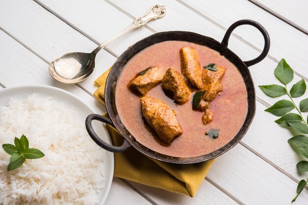 Leckeres Fischcurry serviert mit weißem gekochtem Basmatireis mit Curryblättern im Hintergrund, beliebtes indisches Küstenessen