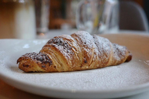 Leckeres, frisch gebackenes Croissant, das im Café auf dem Teller liegt