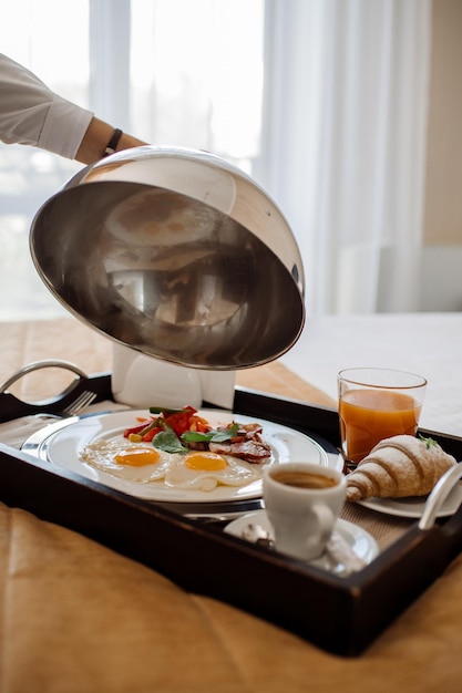 Leckeres frisches Frühstück mit Rührei und Gemüse im Bett im Hotelzimmer