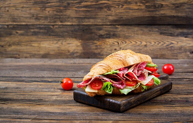 Leckeres Frühstück. Appetitlich Croissant mit Salami und, Käse und Tomaten