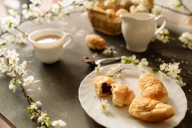 Foto leckeres frühstück: kaffee mit milch und croissants auf dunklem hintergrund