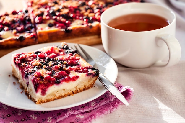 Leckeres Frühstück. Leckerer Kuchen mit verschiedenen Beeren und Hüttenkäse und einer Tasse Tee