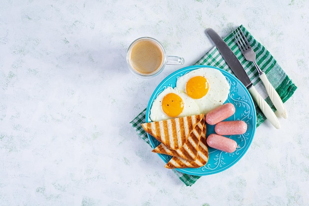 Leckeres Frühstück mit Eiern, Würstchen, Toast und Tasse Kaffee. Amerikanisches Frühstück. Ansicht von oben