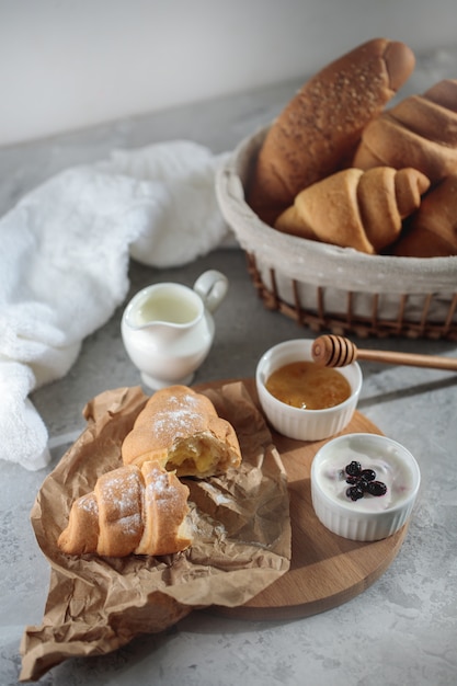 Leckeres Frühstück mit französischem Croissant, mit einer Schüssel Honig und Sahne. Frisches Gebäck. Nahansicht.