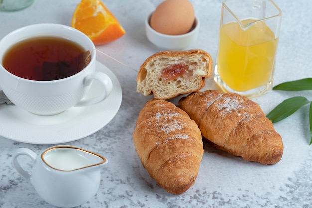 Leckeres Frühstück mit frischen Croissants und einer Tasse schwarzen heißen Tee.