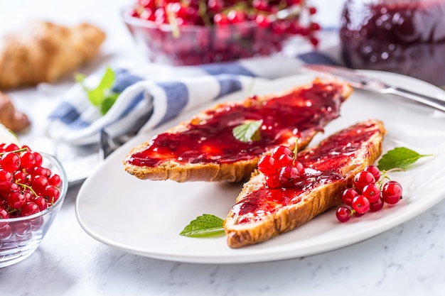 Leckeres Frühstück mit Johannisbeer-Marmelade-Croissants-Butter und Minzblättern.