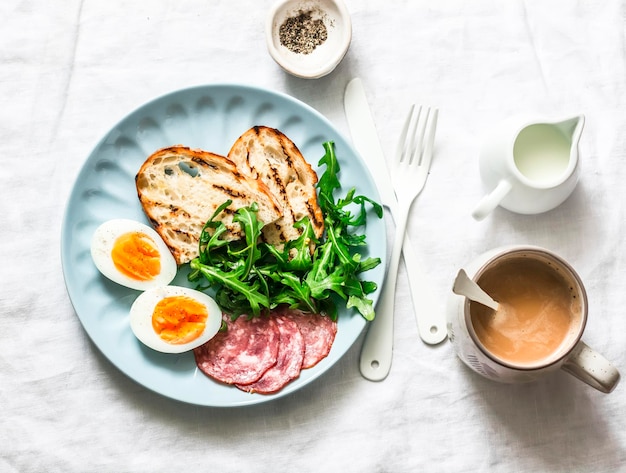 Leckeres Frühstück oder Snack Salamiwurst gekochtes Ei Rucola gegrilltes Brot und Kaffee