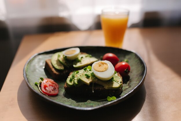 Leckeres Frühstück zu Hause. Sandwich mit frisch geschnittener Avocado über geröstetem Roggenbrot mit Kirsche