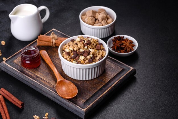 Leckeres, gesundes Frühstück mit Müsli, Müsli, Schokoladenmilch und Marmelade auf dunklem Betonhintergrund