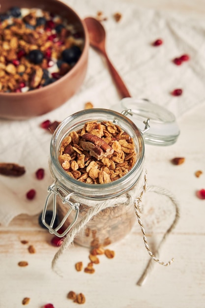 Leckeres gesundes veganes Müsli mit Pekannüssen in einer fruchtigen Schüssel mit Joghurt auf einem weißen Tisch