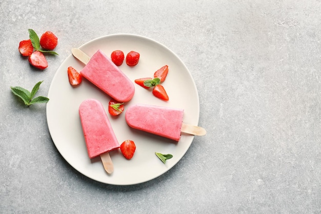 Leckeres Joghurteis mit Erdbeeren auf grauem Hintergrund