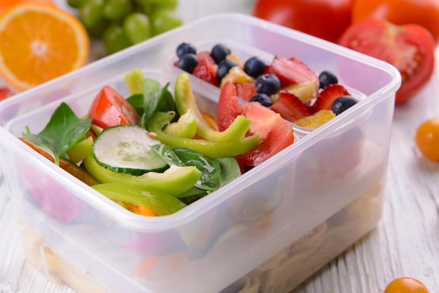 Leckeres Mittagessen in Plastikbehältern auf Holztisch schließen oben