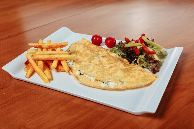 Foto leckeres omelett mit fleisch- und frühstücksteller auf dem tisch.