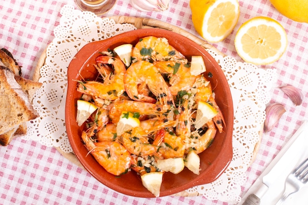 Leckeres portugiesisches Essen mit gebratenen Garnelen, gewürzt mit Knoblauch, Olivenöl und Petersilie, serviert mit geröstetem Brot.