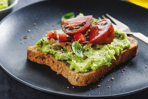 Leckeres Sandwich auf Vollkornbrot mit zerdrückter Avocado und Tomaten