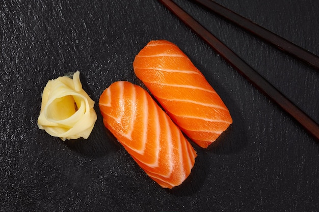 Leckeres Sushi mit Lachs auf schwarzem Hintergrund