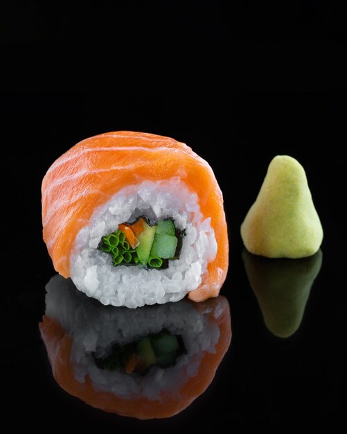 Foto leckeres sushi mit rotem fisch auf schwarzem hintergrund