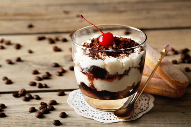 Leckeres Tiramisu-Dessert im Glas auf Holzhintergrund