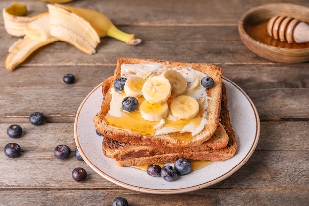 Leckeres Toastbrot mit Honig, Butter und Früchten auf Teller