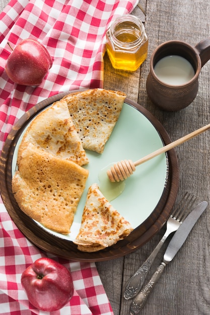 Leckeres traditionelles russisches Frühstück von Pfannkuchen mit Honig auf Teller. Rustikaler Stil.