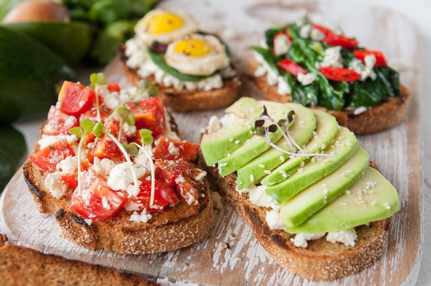 Leckeres und leckeres Bruschetta mit Tomaten, Spinat, Feta-Avocado-Paprika und Blauschimmelkäse.