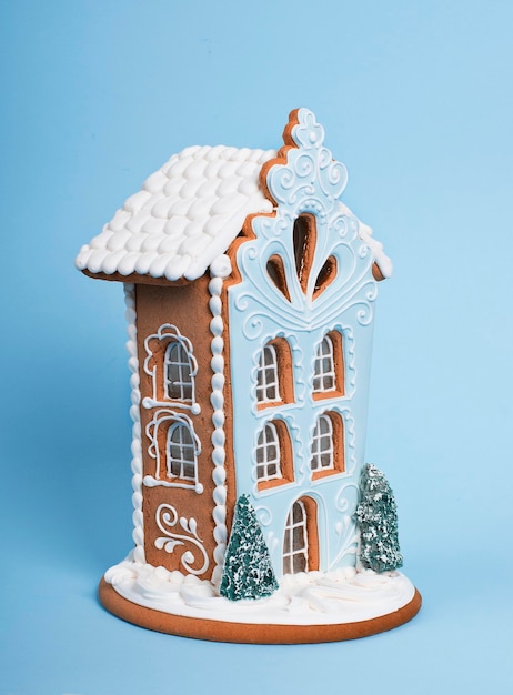 Leckeres und süßes Lebkuchenhaus isoliert auf blauem Hintergrund Konzept des neuen Jahres und der frohen Weihnachten
