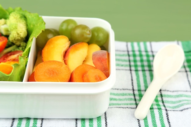 Leckeres vegetarisches Essen in Plastikbox auf grünem Holztisch