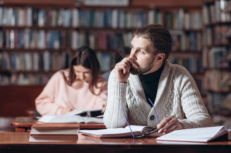 Lector barbudo con ropa informal sentado en la biblioteca