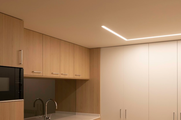 LED-Streifen an der Decke zur Beleuchtung des modernen Küchenbereichs aus Holz