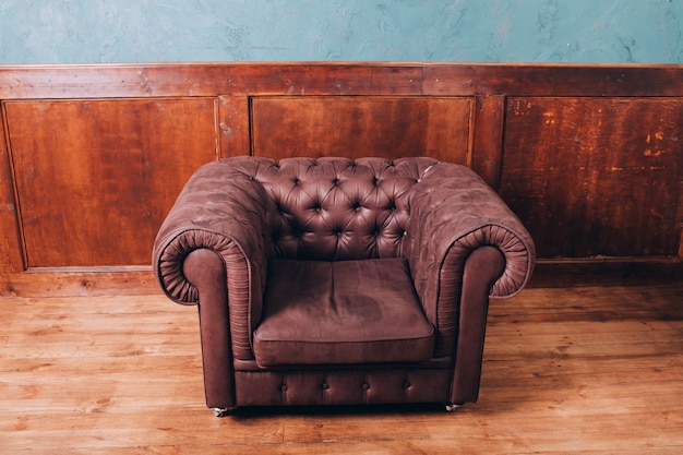 Foto leder retro sofa im büro. ledersofa auf einem holz. ledersessel mit knöpfen.