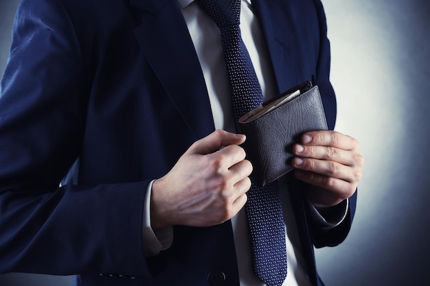 Lederbrieftasche mit Geld in den männlichen Händen auf dunklem Hintergrund