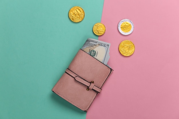 Ledergeldbörse mit Hundert-Dollar-Scheinen und Münzen auf einem blau-rosa Pastell