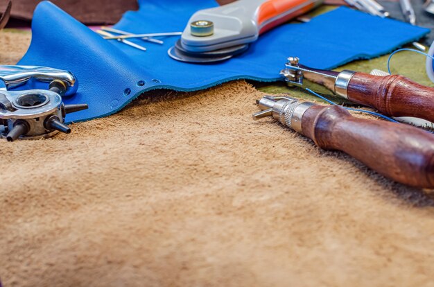 Lederhandwerkswerkzeuge auf Lederhintergrund, Platz für Text, Kopienraum. Schuhmacher-Konzept aus Leder.