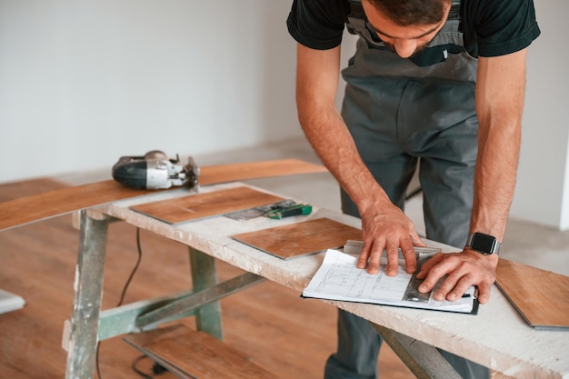 Leer la información El hombre está instalando un nuevo piso de madera laminada