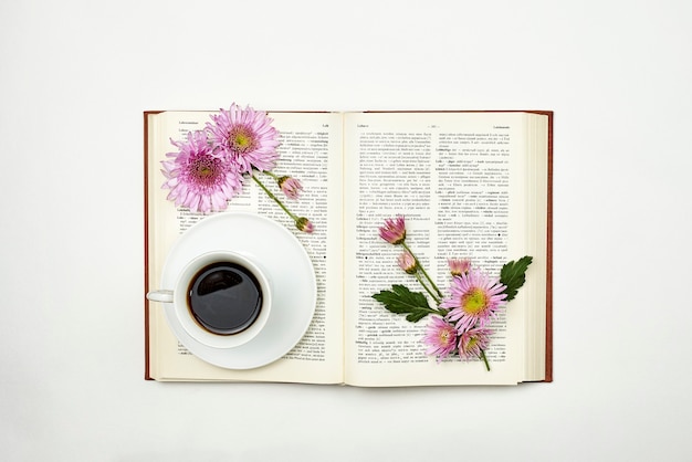 Leer un libro en primavera. Un libro con flores frescas de primavera y una taza de café. Mañana acogedora con