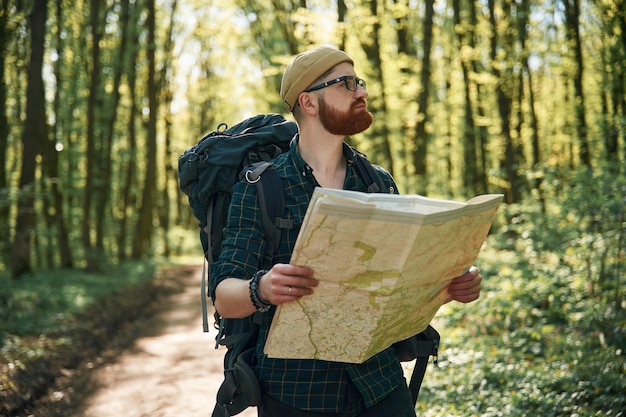 Leer el mapa buscando un camino El hombre barbudo está en el bosque durante el día