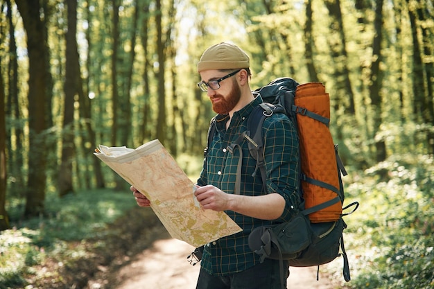 Leer el mapa buscando un camino El hombre barbudo está en el bosque durante el día