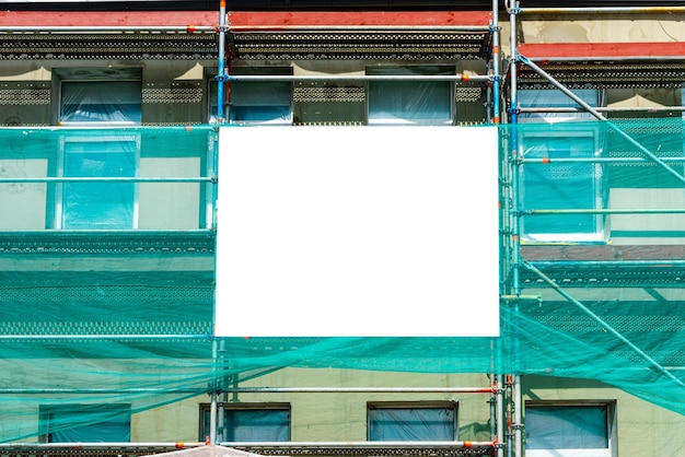 Leer Modell für Außenwerbung mit Kopierfläche an der Wand des im Bau befindlichen Gebäudes mit Gerüst. Leere Informationstafel an einer renovierten Fassade