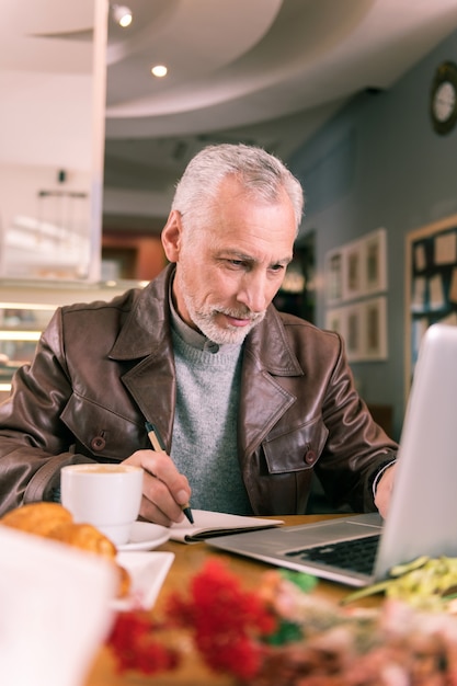 Leer reseñas. Emocionado, famoso escritor experimentado leyendo reseñas en línea de su nueva novela en una computadora portátil