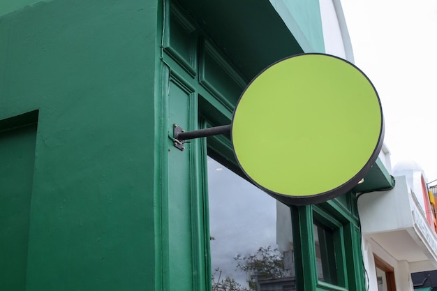 Leere abgerundete Ladenschilder für Mockup Abgerundete Schildtafel, die an der grünen Wand aufgehängt wird