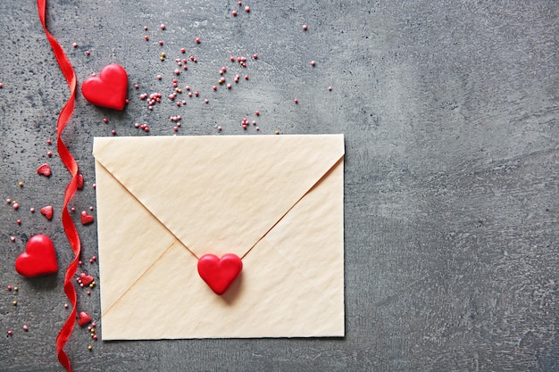 Leere anwesende Valentinskarte mit kleinen Herzen auf grauem strukturiertem Hintergrund