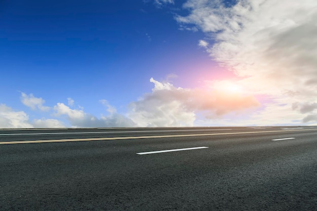 Leere Autobahnasphaltstraße und schöne Himmelssonnenunterganglandschaft