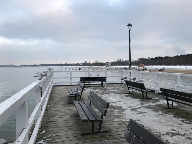 Foto leere bank am pier am meer gegen den himmel